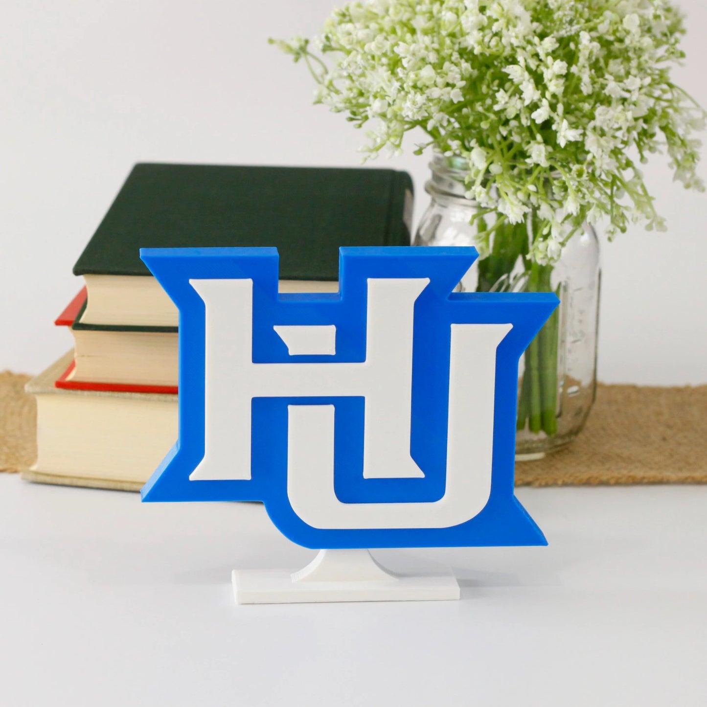 Hampton University decoration in front of a stack of books and mason jar with baby's breath flowers.
