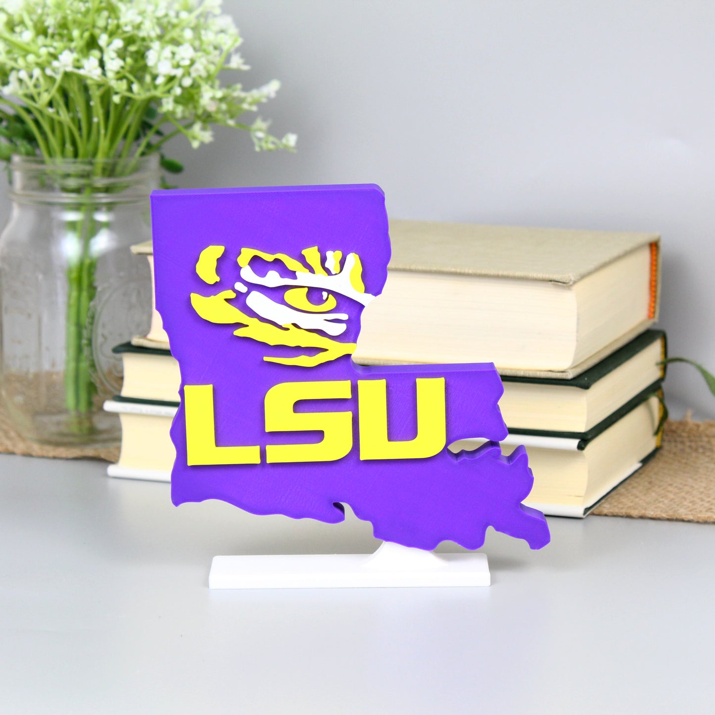 Louisiana State University decoration in front of a stack of books and mason jar with baby's breath flowers.