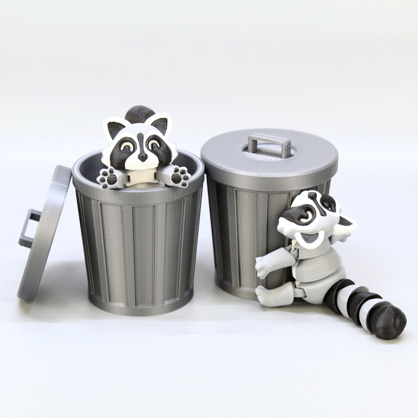 A set of two raccoons playing around two trashcans.