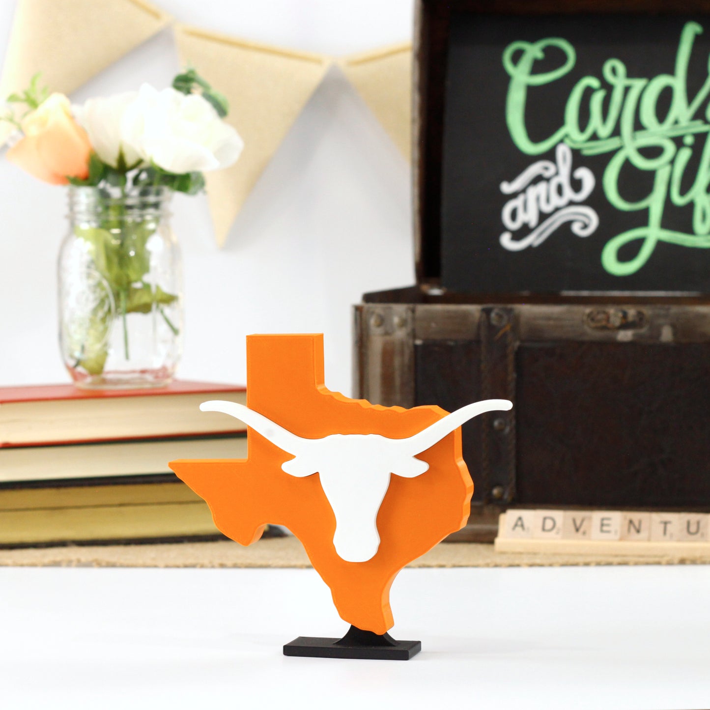 University of Texas decoration in front of a stack of books and a chest for cards and gifts. Adventure in Scrabble titles.