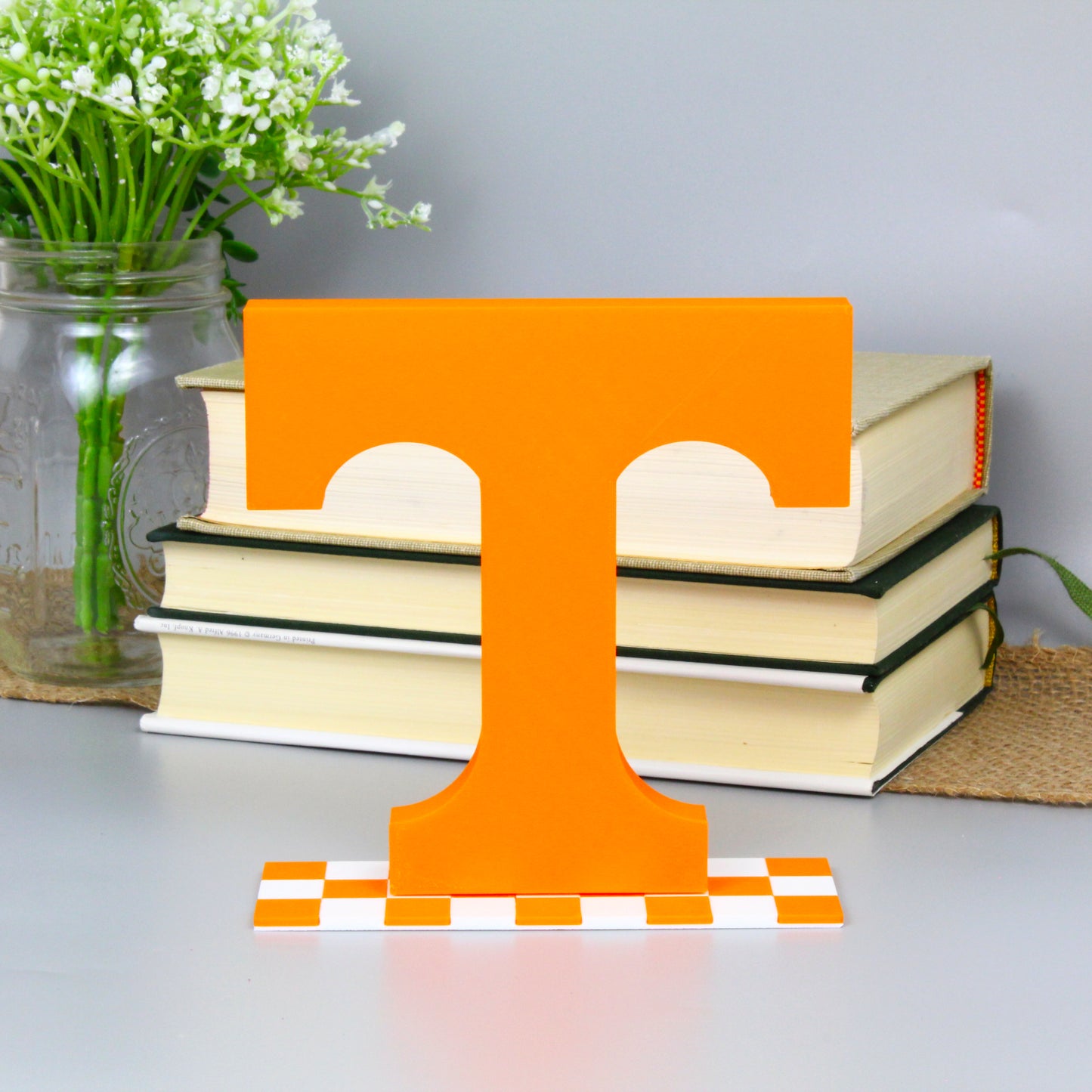 University of Tennessee decoration in front of a stack of books and mason jar with baby's breath flowers.
