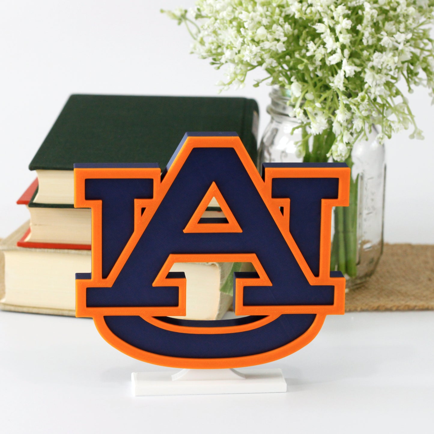 University of Auburn decoration in front of a stack of books and mason jar with baby's breath flowers.