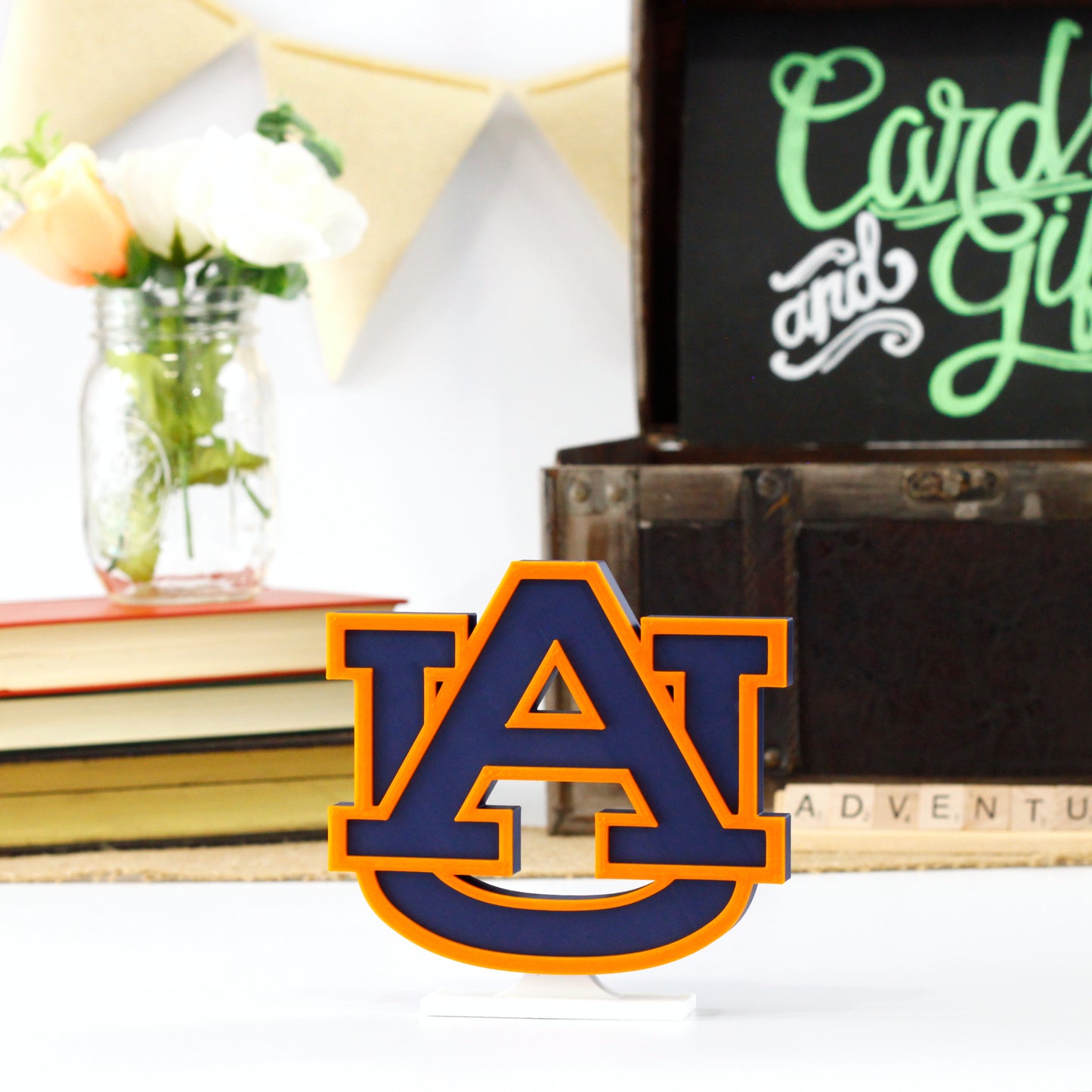 University of Auburn decoration in front of a stack of books and a chest for cards and gifts. Adventure in Scrabble titles.