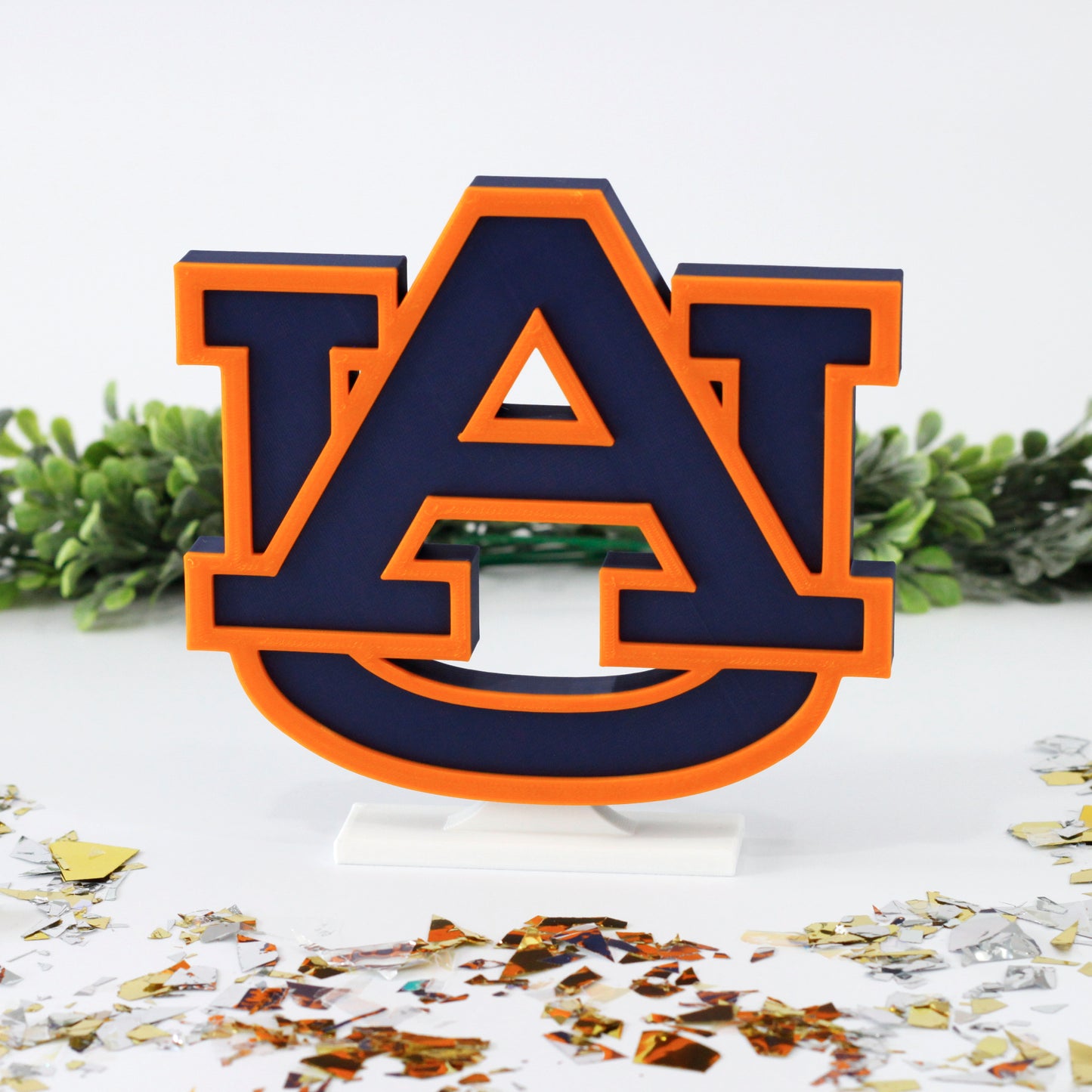 University of Auburn decoration surrounded by glitter with ivy behind it.