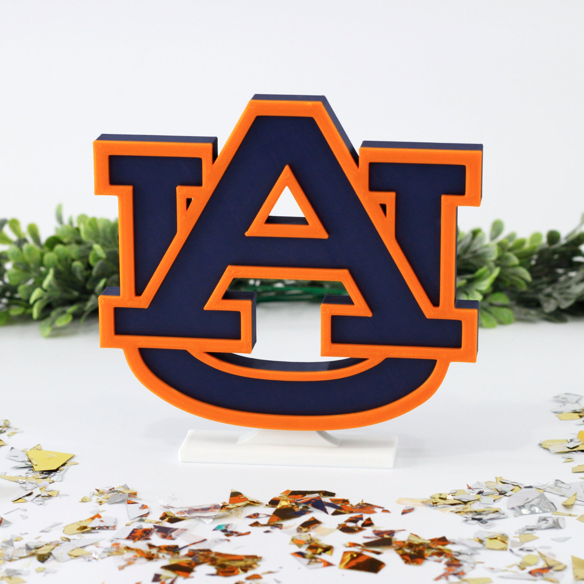 University of Auburn decoration surrounded by glitter with ivy behind it.