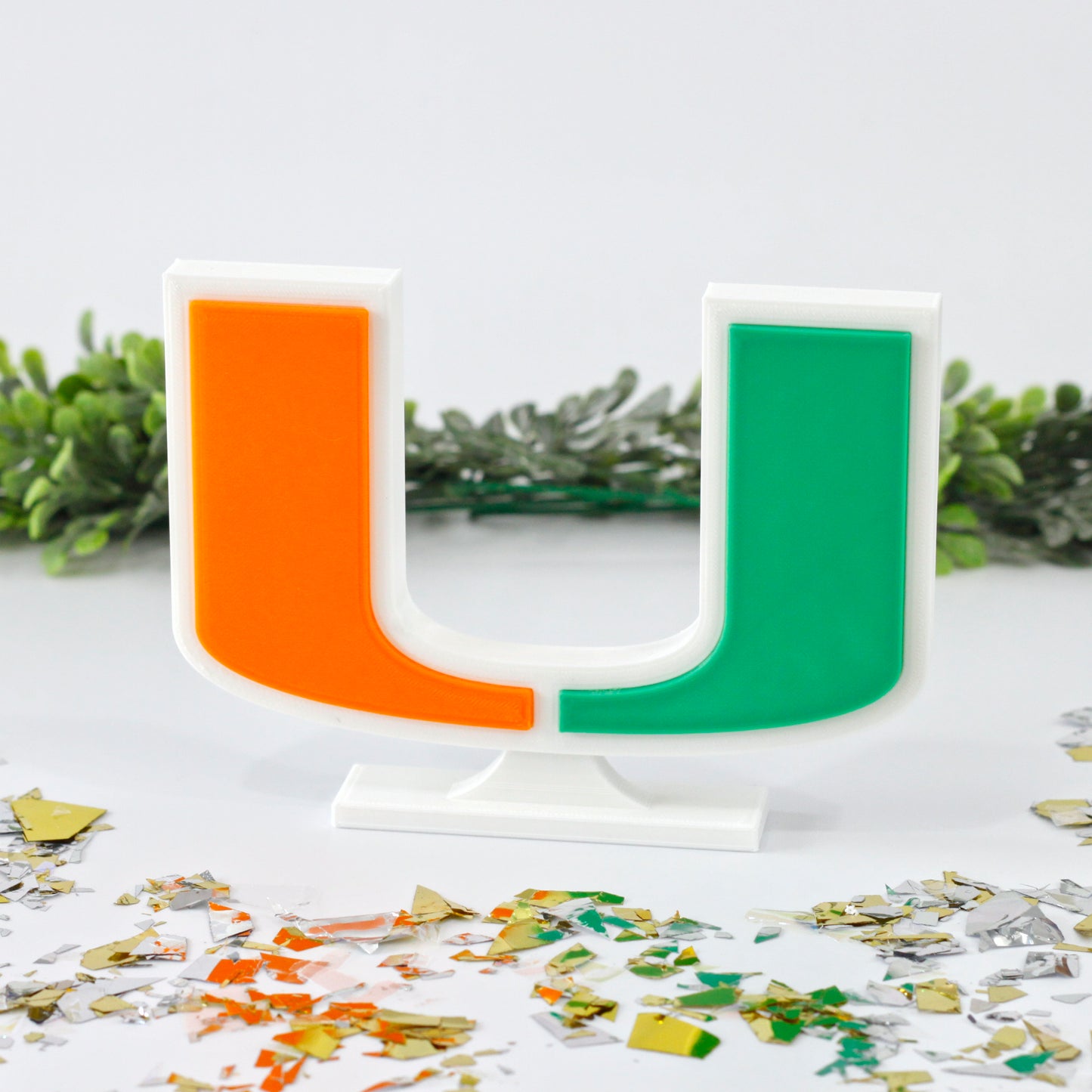 University of Miami decoration surrounded by glitter with ivy behind it.