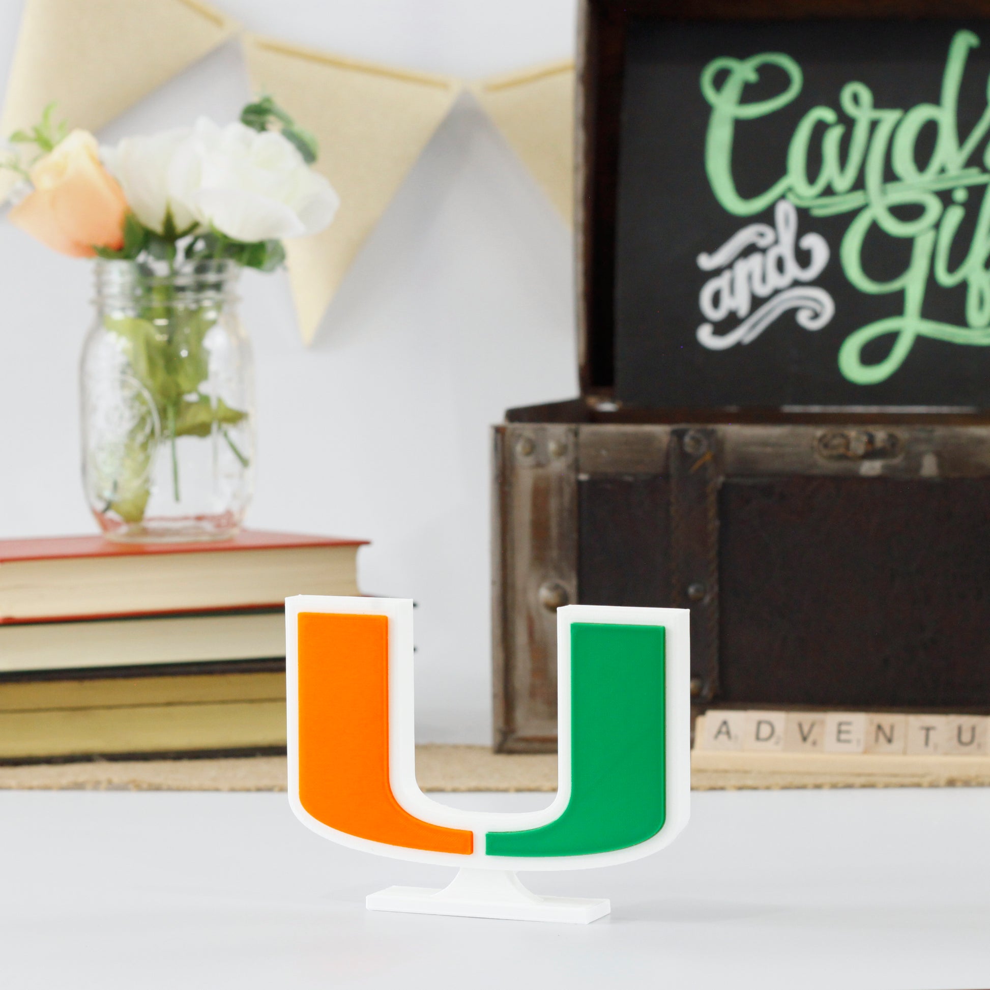 University of Miami decoration in front of a stack of books and a chest for cards and gifts. Adventure in Scrabble titles.