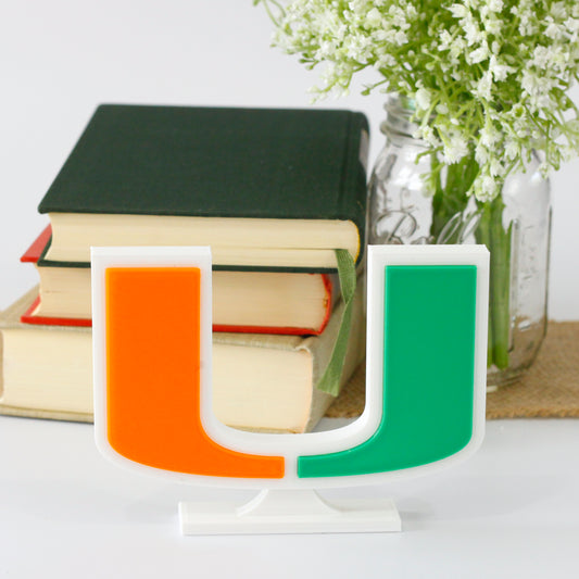 University of Miami decoration in front of a stack of books and mason jar with baby's breath flowers.