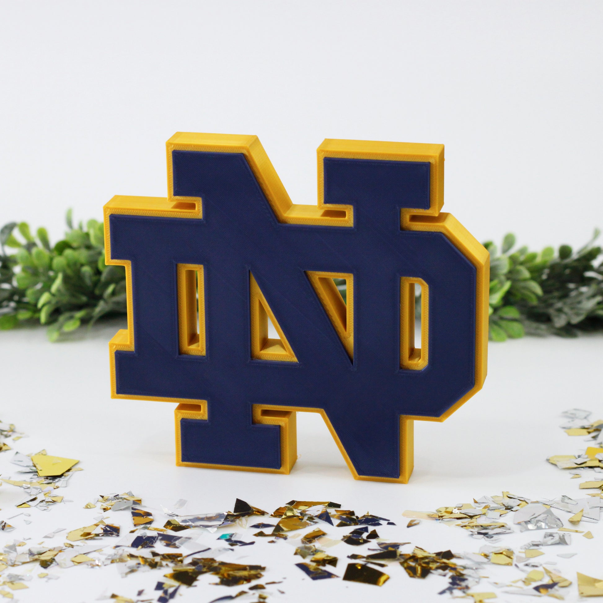 University of Notre Dame decoration surrounded with glitter with ivy behind it.