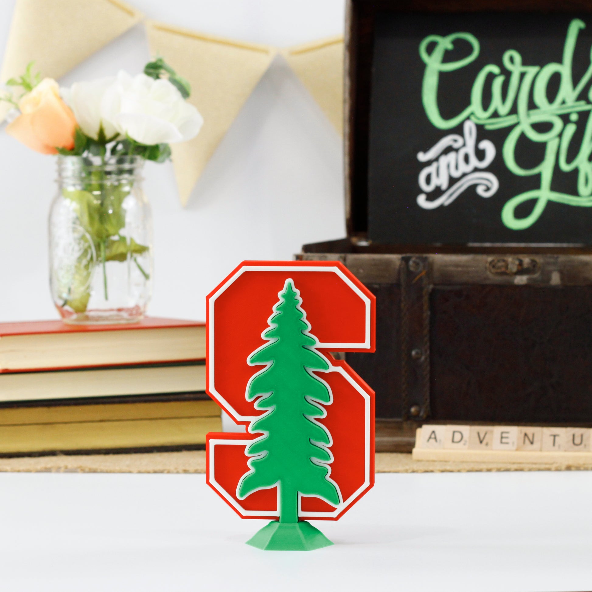 Stanford University Cardinals decoration in front of a stack of books and a chest for cards and gifts. Adventure in Scrabble titles.