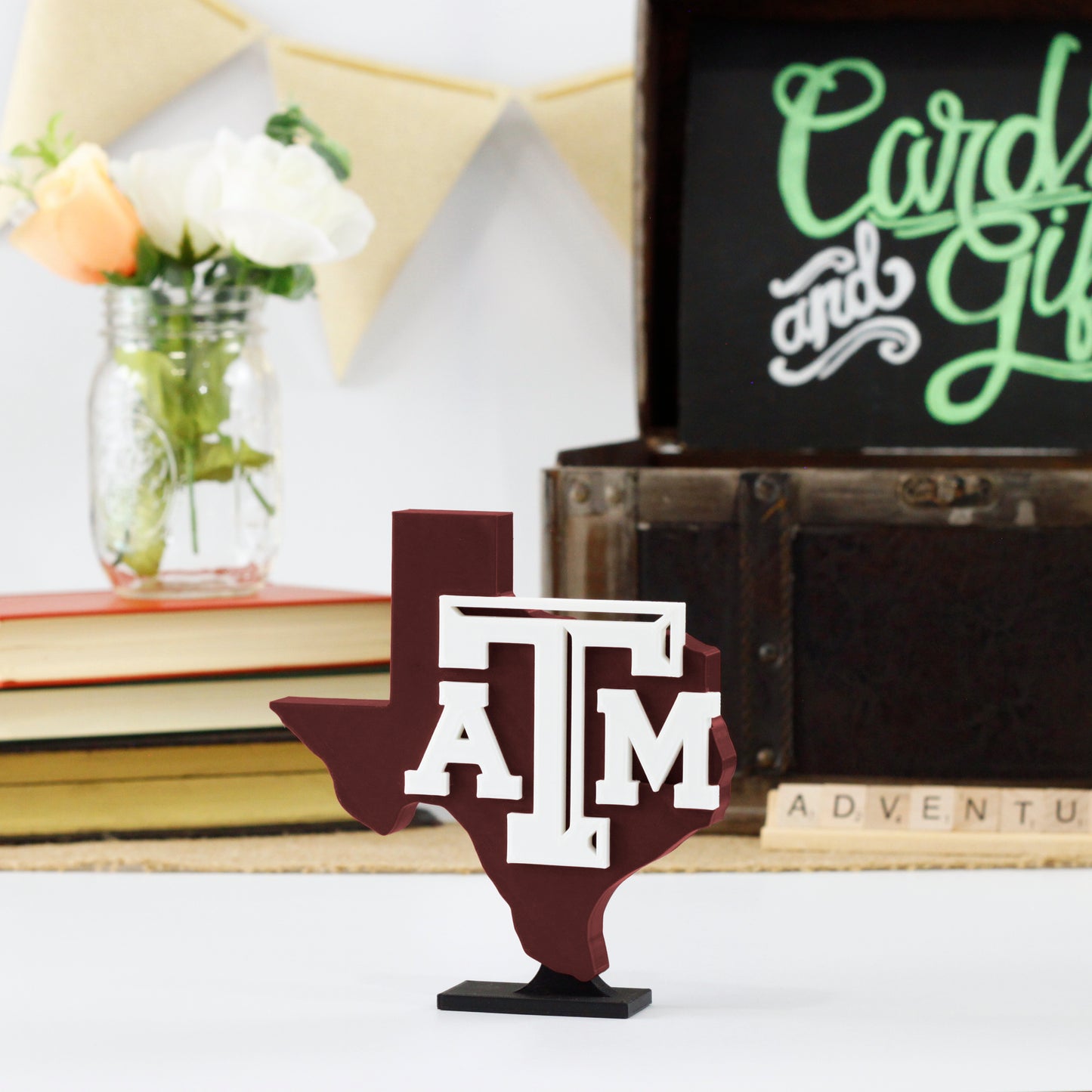 University of Texas A&M decoration in front of a stack of books and a chest for cards and gifts. Adventure in Scrabble titles.